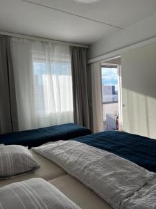 1 Schlafzimmer mit 2 Betten und einem großen Fenster in der Unterkunft Top floor flat with sauna, A/C & free parking in Vantaa
