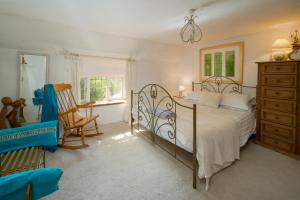 a bedroom with a bed and a chair and a dresser at Lobster Cottage in Ventnor