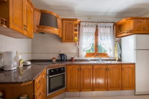a kitchen with wooden cabinets and a sink and a refrigerator at Villa Llobell - Plusholidays in Moraira