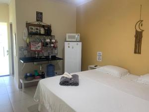 a bedroom with a white bed and a refrigerator at Portal Mágico in Itacaré