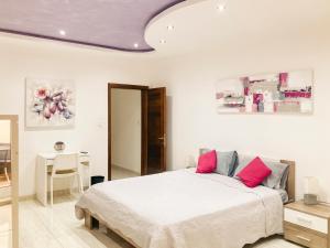 um quarto com uma cama branca e almofadas cor-de-rosa em Harbour Pearl em Kalkara