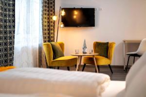 a room with chairs and a table and a tv at City Hotel Meckenheim in Meckenheim