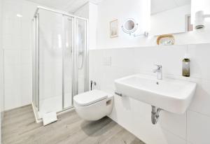 biała łazienka z toaletą i umywalką w obiekcie City Hotel Meckenheim w mieście Meckenheim