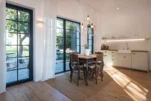 a kitchen with a table and chairs and windows at Ateliér v raji in Spišské Tomášovce