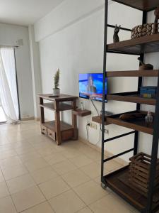ein Wohnzimmer mit Fernseher, Schreibtisch und Regal in der Unterkunft Baires Garden in Buenos Aires