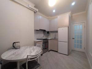 a small kitchen with a table and a white refrigerator at AURA on Jumabek street 233 in Bishkek +14 photos