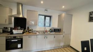 a kitchen with white cabinets and a sink and a microwave at Chapel Row Cottages 5 in Wirksworth
