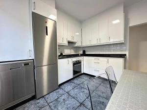 a kitchen with white cabinets and a stainless steel refrigerator at O fogar da nube in Ourense