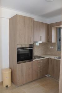 a kitchen with wooden cabinets and a black oven at ALTAVILLAS Apartment 6 KYRA in Kakí Vígla