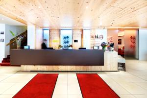 a lobby with a reception desk and a red rug at Drei Loewen in Munich