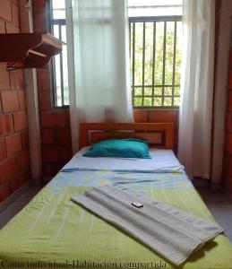 Una cama con una toalla y una ventana en Hostal Ariantiy, en Pepino