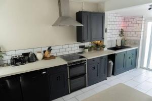 uma cozinha com armários azuis e uma bancada em Large Home Sleeps 6 Central Location Free Parking em Plymouth