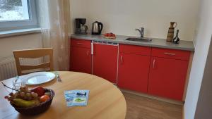 eine Küche mit roten Schränken und einem Tisch mit einer Schale Obst in der Unterkunft Ferienpark Thüringer Wald in Schalkau