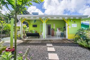 a yellow house with a deck with a table at Ti-colibri ✓Iguana Village in Sainte-Luce