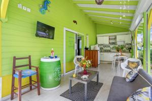 a room with a green wall with chairs and a table at Ti-colibri ✓Iguana Village in Sainte-Luce