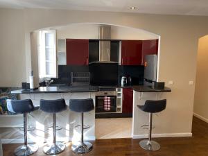 a kitchen with red cabinets and blue bar stools at Bel appartement proche de Paris in Colombes