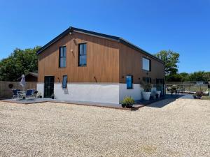 a large wooden house with a gravel yard at The Paddocks - Spacious annexe with rural outlook. in Wareham