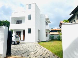 a white house with a car parked in front of it at TwinsTop Villa in Minuwangoda