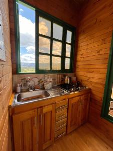 a kitchen with a sink and a window in a log cabin at Huitaca Glamping in Paipa