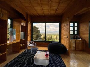 una sala de estar con una gran ventana en una cabaña en Huitaca Glamping, en Paipa