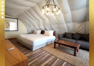 a bedroom with a bed and a couch in a tent at Desert Breeze Cocoon in Ras al Khaimah