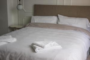 uma cama branca com duas toalhas dobráveis em Alójate en el corazón de Mendoza . Angélica Downtown em Mendoza