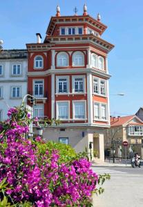 a large red building with a tower on a street at Mirador Porta da Vila, Noia in Noya