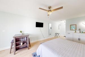 a white bedroom with a bed and a flat screen tv at Capri 103 in Marco Island