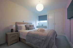 a bedroom with a large bed with a lamp and a table at 2 bed spacious apartment in Cardiff CC in Cardiff