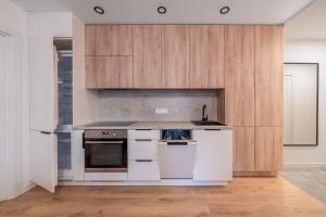 a kitchen with white appliances and wooden cabinets at Modern 2 bedroom Vytenio apartment in city centre I Self check-in in Vilnius