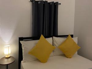 un letto con 2 cuscini gialli e una tenda nera di Dreamink farm og Myl`s place a Sorsogon