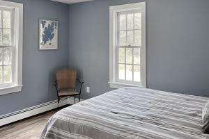 Tenants HarborにあるCoastal Charmerの青い壁のベッドルーム1室、ベッド1台、椅子1脚が備わります。