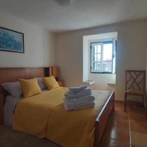 1 dormitorio con 1 cama con sábanas amarillas y ventana en Casa do Cruzeiro, en Castanheiro