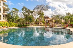 a swimming pool at a resort with trees and buildings at RELAX TULUM Family Friendly Apartment in the in the jungle - pools & cenotes in Tulum
