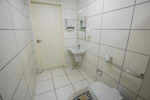ein weißes Bad mit einem WC und einem Waschbecken in der Unterkunft City Hotel, Curitiba in Curitiba