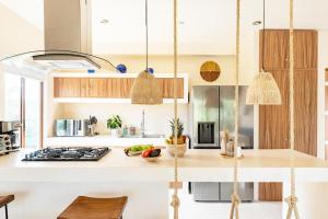 a kitchen with white countertops and wooden cabinets at RELAX TULUM Family Friendly Apartment in the in the jungle - pools & cenotes in Tulum
