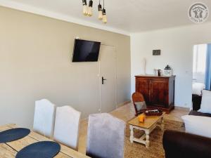 un salon avec une table et une télévision au mur dans l'établissement Gîte calme avec jardin clôturé, animaux acceptés, parking et WIFI à Viels-Maisons - FR-1-532-21, à Viels-Maisons