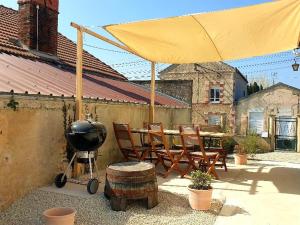 - un barbecue et des chaises sous un grand parapluie jaune dans l'établissement Gîte calme avec jardin clôturé, animaux acceptés, parking et WIFI à Viels-Maisons - FR-1-532-21, à Viels-Maisons