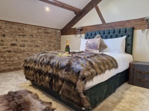 a bedroom with a large bed with a blanket and a bottle of champagne at The Hamilton luxury holiday let's- The Coach House with hot tub in Scorton