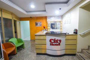 a lobby of a city hotel with a counter and chairs at City Hotel, Curitiba in Curitiba