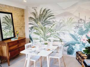 a dining room with a table with white chairs and a mural at Maison de village charmante avec jardin et terrasse, proche de Soissons, idéale familles et animaux acceptés - FR-1-532-19 in Buzancy