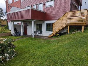 una casa roja con una terraza de madera en un patio en Mountain & Sea View Apartment Tromsø, en Tromsø
