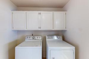 a kitchen with white cabinets and a washer and dryer at Traditions in College Station