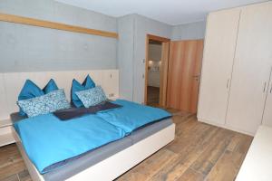 um quarto com uma cama com lençóis azuis e almofadas azuis em Chesa Bunita Trais em Gaschurn