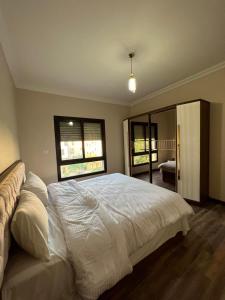 a bedroom with a large white bed and two windows at القاهره حلوان تقسيم سلاح المهندسين شارع الجبل in Sheikh Zayed