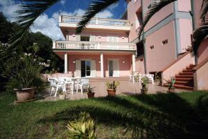 une maison rose avec une table et des chaises dans une cour dans l'établissement Residence Happy, à Marina di Pietrasanta