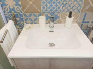 - un lavabo blanc dans la salle de bains avec 2 bouteilles dans l'établissement Eraclea Minoa Apartments, à Eraclea Minoa