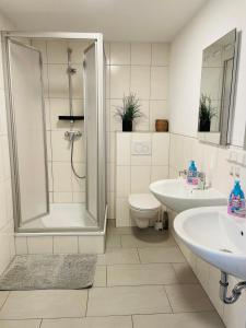 a bathroom with a shower and two sinks and a toilet at Ferienwohnung DeuxPonts II in Rimschweiler