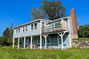 a blue house with a balcony on top of it at Lobster Tail Cottage in Castine
