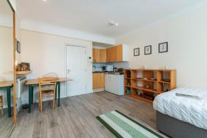 a bedroom with a bed and a desk and a kitchen at Elegant Art Deco whole apartment 2mins to Hyde Park, 8mins to Bayswater, Nottinghill, Paddington in London